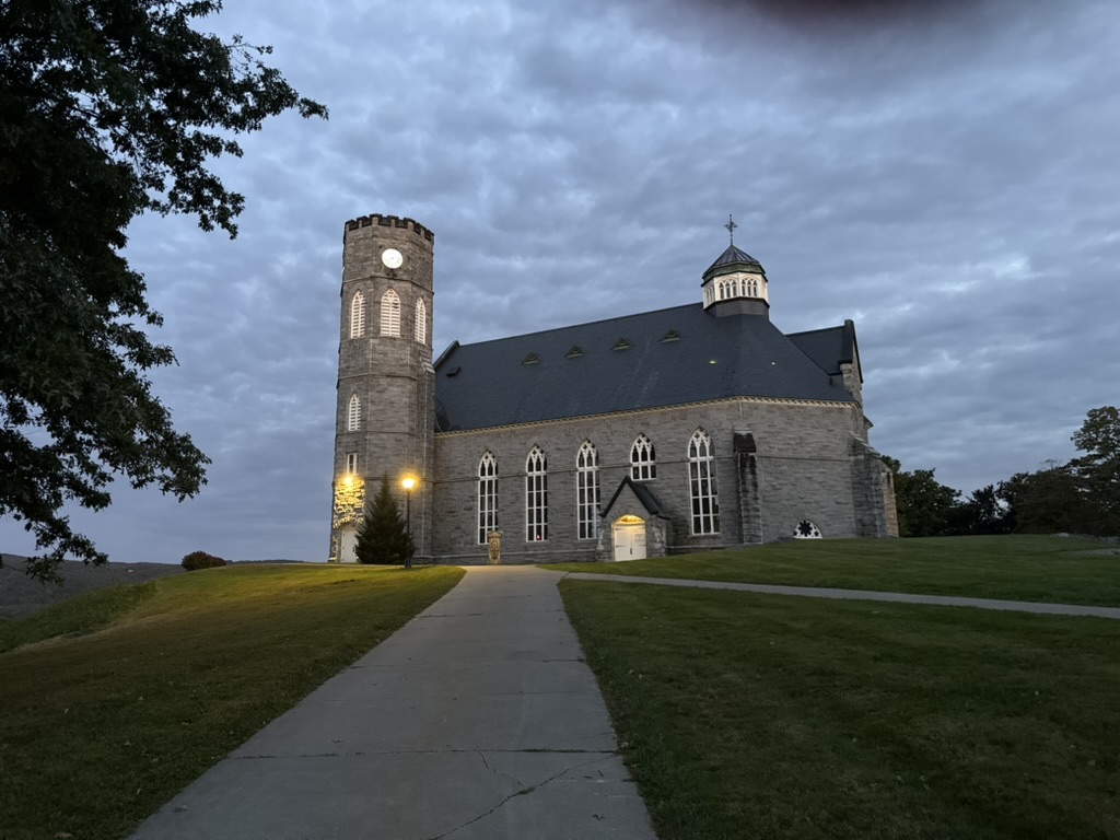 The chapel beneath a cloudy evening sky with lamps glowing